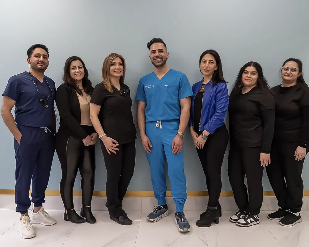 Dental Health Dr. Rashin Elahi standing in front of Smile Dental Toronto logo with a bright smile, representing quality dental care