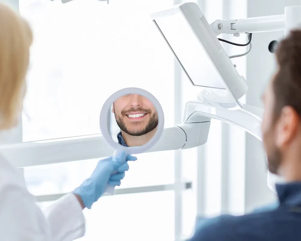 A man smiling in a dental chair during prophylaxis treatment