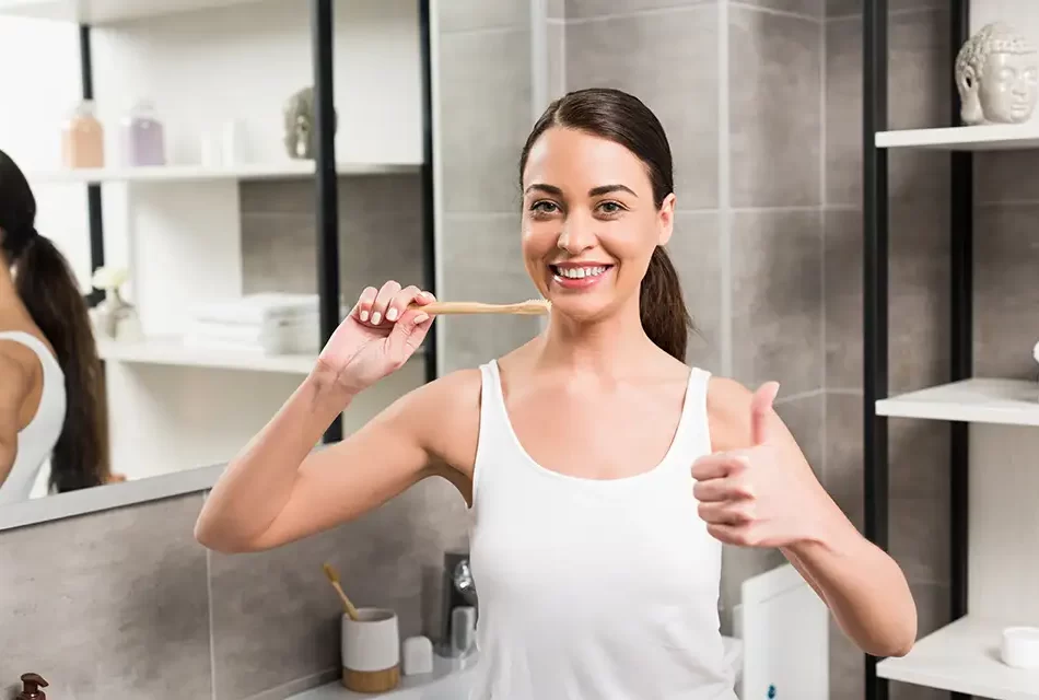 cheerful-woman-showing-thumb-up-while-holding-toothbrush cheerful-woman-showing-thumb-up-while-holding-toothbrush