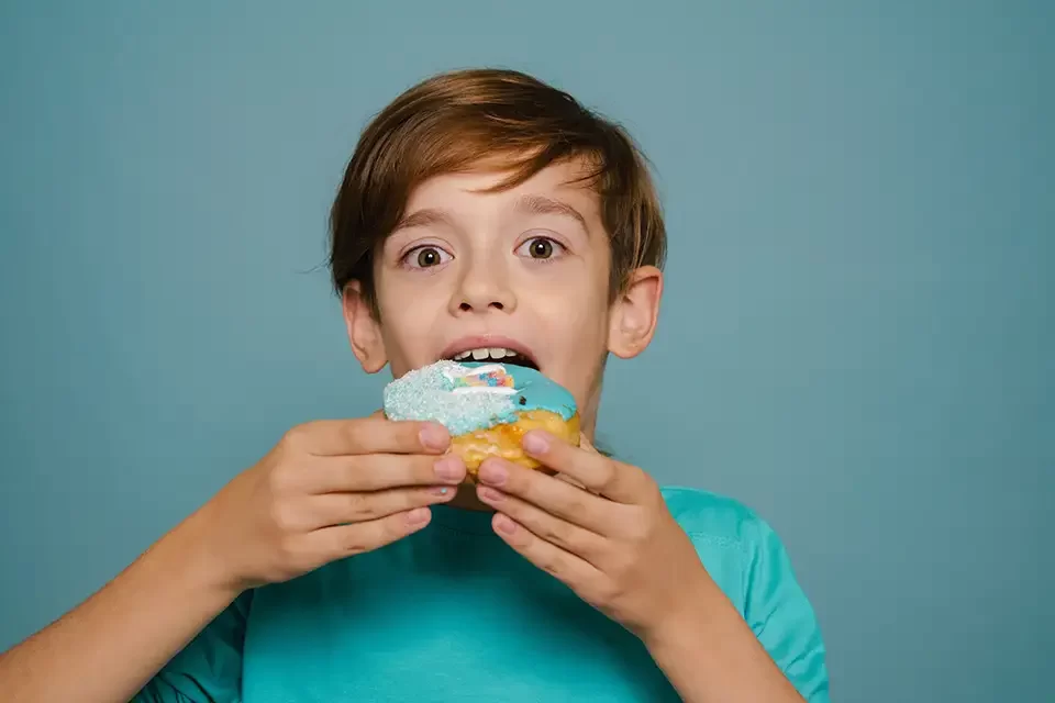 ginger-white-boy-wearing-long-sleeve-eating-doughnut Preventing the Impact of Sugary Foods on Kids' Dental Health
