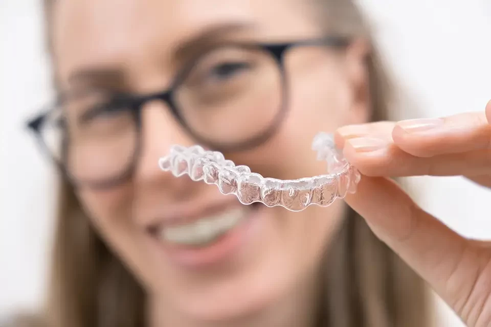 smiling-woman-using-clear-plastic-removable-braces Does Invisalign Hurt? Comparing Invisalign with Traditional Braces