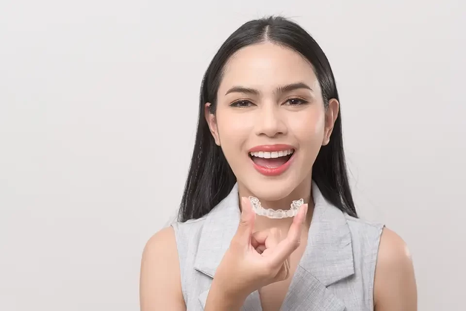 young-smiling-woman-holding-invisalign-braces